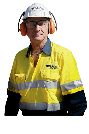 A man wearing yellow and blue NPS high-visibility work wear, safety hat, glasses and ear protection looks at the camera.