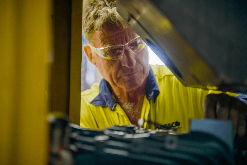A Perth compressor service technician from Nessco Pressure Systems repairs a large, yellow compressor.