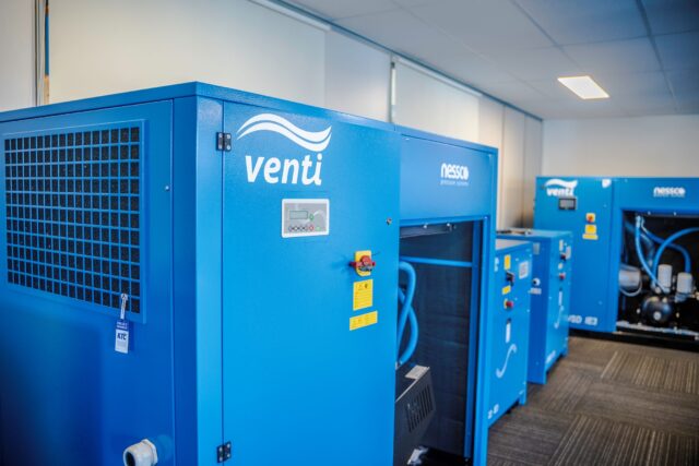 Four bright blue Venti compressors in a sales showroom.